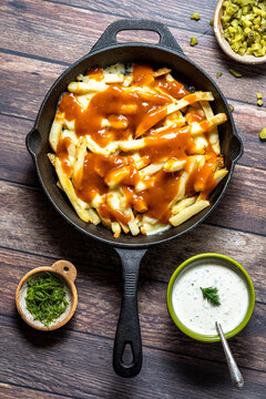 Above view of a skillet of poutine with toppings all around.