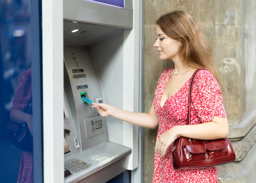 Girl uses ATM, withdraws cash from card. Girl buys travel ticket from machine