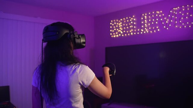 Young woman wearing VR headset playing and pointing controller at virtual object interacting with digital space and controlling process in modern gaming experience