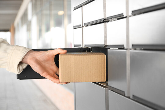 Man taking out cardboard box from parcel locker outdoors, closeup