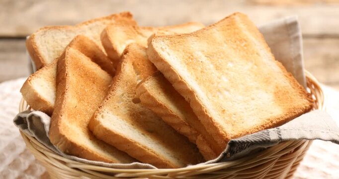 Browned toast bread slices in wicker basket on wooden table, closeup