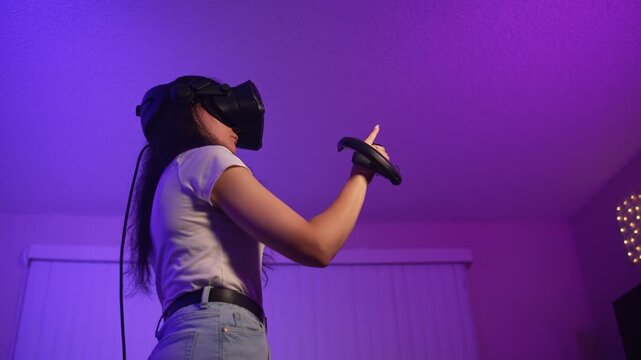 Young woman wearing VR headset reaching forward controlling virtual environment interacting with digital space and entering modern interactive gameplay experience