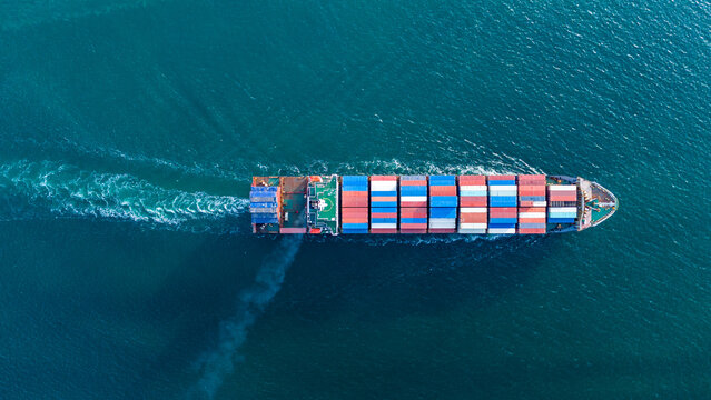 large cargo container ship fully loaded with colorful containers sailing through the deep blue ocean. Global maritime trade, freight transport and logistics business.