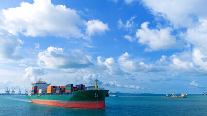 Fototapeta premium Side view of a large green cargo container ship sailing on the sea under a bright blue sky with fluffy white clouds. Global shipping logistics, maritime transport, and international trade.