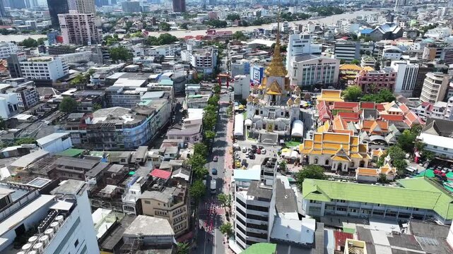 Wat Traimit temple with golden pagoda structure, Temple complex stands within dense city area near Chinatown district.
