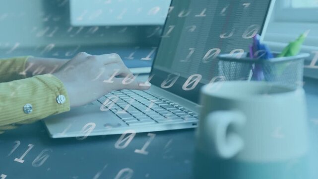 Woman typing on laptop at tech desk while grabbing mug, binary overlay animating across screen