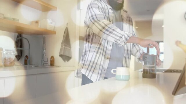 Man placing blue mug, pressing French press plunger on island, bokeh overlay showing coffee prep