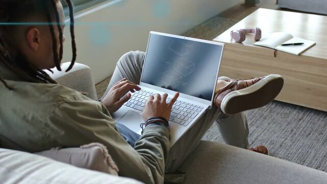 Man typing on laptop on sofa initiating wireframe graphics and blue streaks for technology work