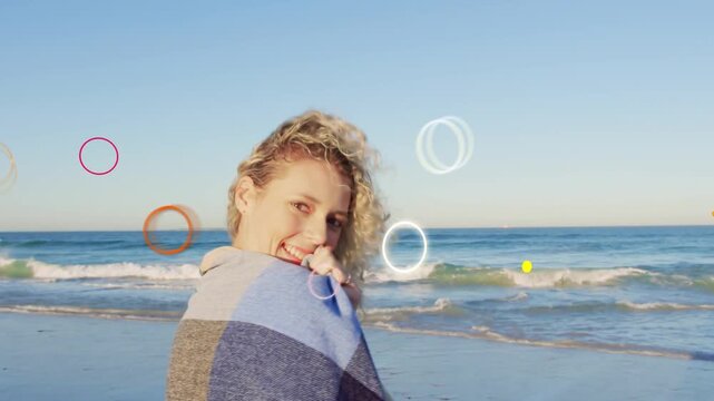 Woman turning toward camera, breeze lifting hair, promoting travel with shawl and shapes overlaying