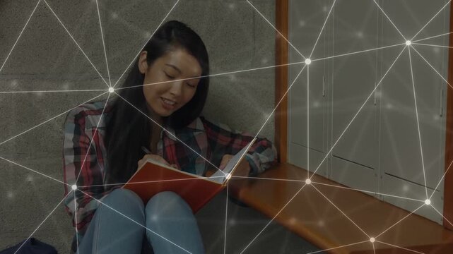 Woman studying in nook opening orange notebook, turning pages while web overlay marking notes