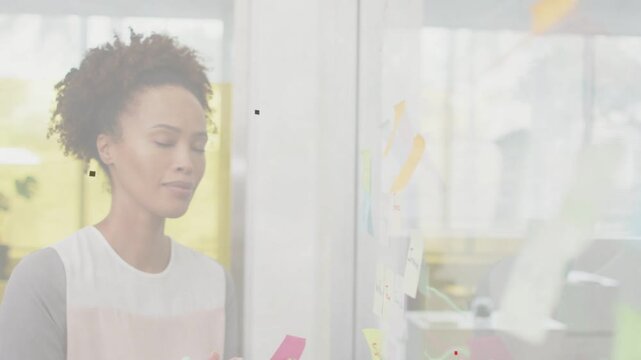 Woman writing then peeling pink sticky note and placing on glass for business planning, smiling