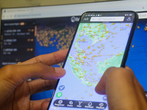 Klaten, Central Java - Indonesia - Jun 28 2024: A person holds a mobile phone to access the Flightradar24 app, which tracks aircraft movements in real-time.