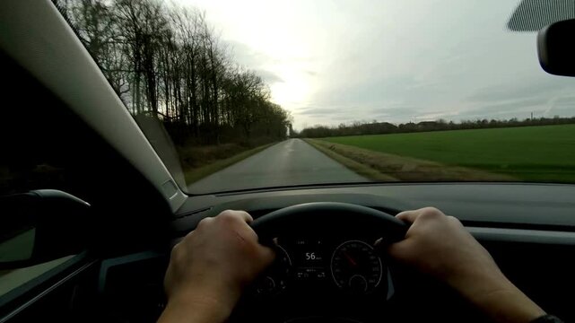 view from a car windshield of natural landscape with road, green tree and and light. traveler driving on trip or journey. First person view of driving a car on countryside roads.