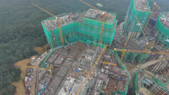 Vietnam, Da Nang, Ba Na Hills Drone Panorama Over Highrise Construction Site At Ba Na Hills Da Nang, Multiple Tower Cranes And Green Netting, Concrete Decks And Steel Rebar, Crane Operator