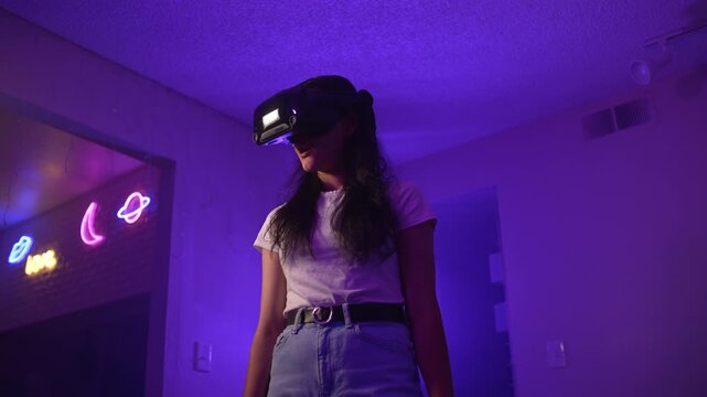 Young woman wearing VR headset raising head reacting to virtual reality entering digital space and experiencing strong emotions from interactive experience