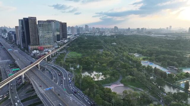 Chatuchak Park with dense trees ponds and walking paths beside city buildings. Green space contrasts with surrounding urban environment.