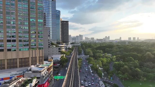BTS skytrain rail line running above roads between buildings and city blocks. Elevated track connects urban areas with transportation system.