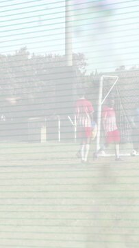Vertical video: Soccer reds pressing ball at goal, keeper diving, blue trio bracing, scanlines