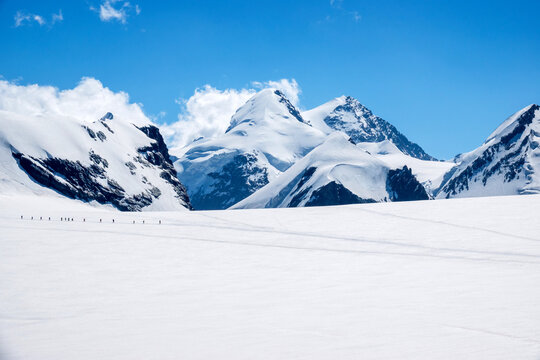 Team of Mountaineers Crossing Glacier Together in Snowy Mountains Spaghetti Tour Route Rifugio Gnifetti Alagna Valsesia, Piedmont / Italy - July 19 2023