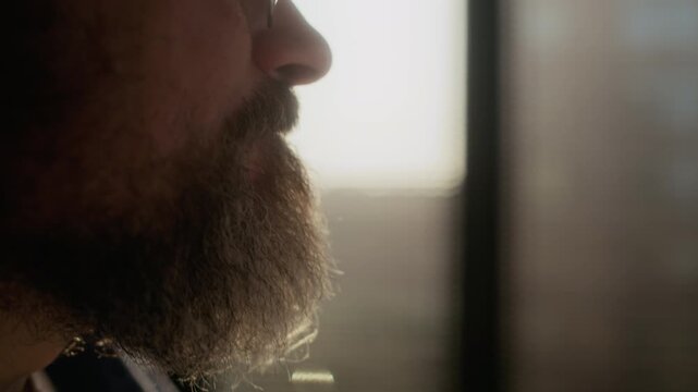 Close up side view of bearded Caucasian novelist holding pencil in hand reading printed draft in home office