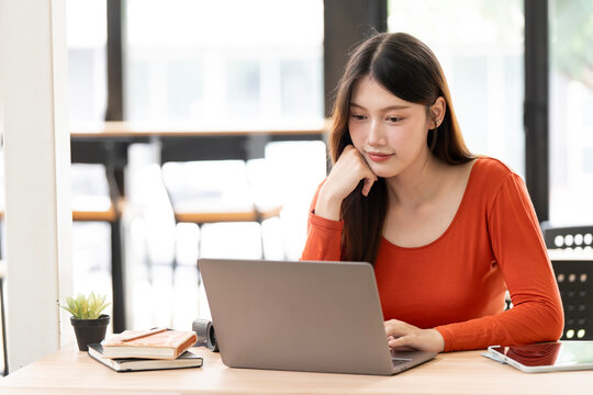 Thoughtful Young Asian Woman Contemplating While Working on Laptop in Cafe