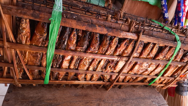 Smoked roa fish clamped with bamboo sticks displayed at a traditional market, highlighting authentic Indonesian seafood, rustic presentation, and local culinary culture.