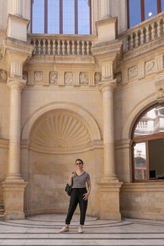 Retrato de cuerpo completo de una mujer en el patio hist&oacute;rico de la Logia en Heracli&oacute;n. Arquitectura renacentista veneciana con hornacinas y detalles en piedra.