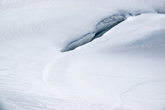Abstract glacier snow texture with smooth minimal surface and subtle crevasse shapes, natural background. Spaghetti Tour Route Rifugio Gnifetti Alagna Valsesia, Piedmont / Italy - July 19 2023