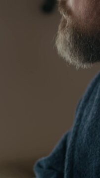 Vertical close up of pensive middle aged Caucasian male author holding pencil in hand sitting indoors, thinking over novel plot