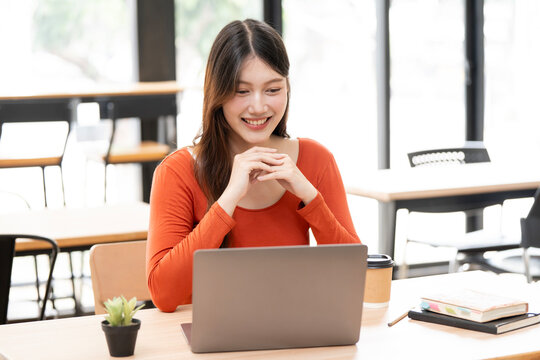 Happy Asian Businesswoman Feeling Satisfied While Working on Laptop in Cafe