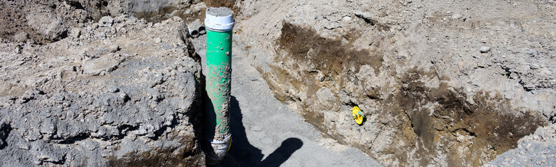 Naklejka premium Residential construction site earthwork, trench dug in ground with 6 inch pipe installed and pipe plug, seal pipe, to cap ends, housing development 