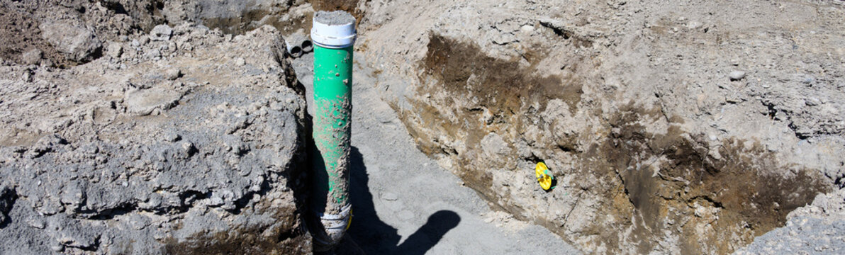 Residential construction site earthwork, trench dug in ground with 6 inch pipe installed and pipe plug, seal pipe, to cap ends, housing development
