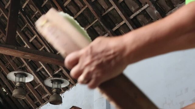 A housewife in a rural area of Java, Indonesia, is winnowing and cleaning rice using a bamboo winnowing tray.
