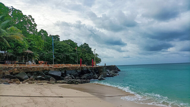 Phi Phi Island on August 15, 2025: Tropical shoreline view with rocky pier and cloudy blue skies