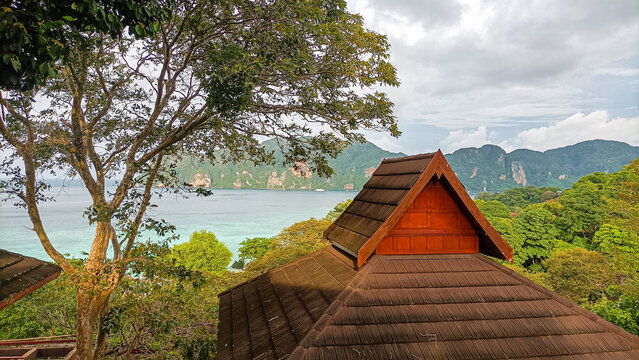 Phi Phi Island on August 15, 2025: Wooden bungalow roof overlooking tropical sea and green hills
