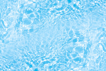 Obraz premium Blue water with ripples on the surface. Defocus blurred transparent blue colored clear calm water surface texture with splashes and bubbles. Water waves with shining pattern texture background.