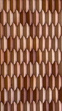 Modern wooden wall texture with geometric 3D pattern. Close-up of vertical brown blocks creating an abstract architectural background. Minimalist interior design element.