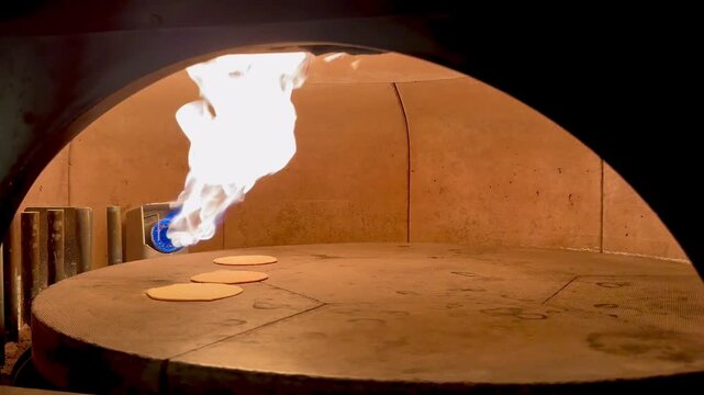 Fresh Pita Bread Inflating in Stone Oven, Industrial Rotating Oven with Burning Flame