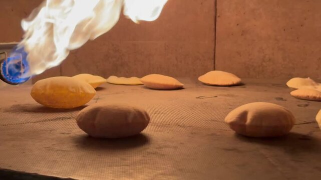 Fresh Pita Bread Inflating in Stone Oven, Industrial Rotating Oven with Burning Flame