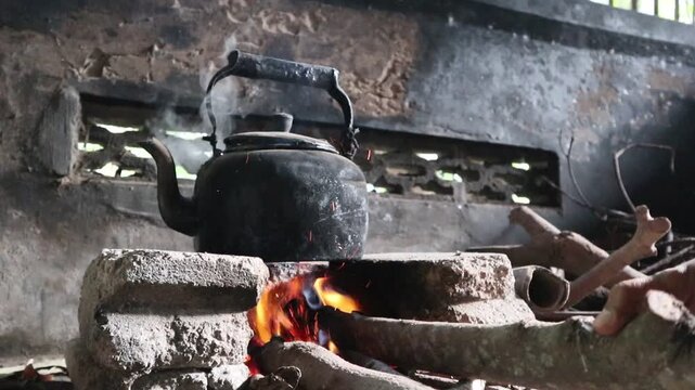 boiling water with an old kettle on a wood stove in a rural area of Java, Indonesia, at a kitchen in a rural area in Indonesia, an old kettle to boil water on a traditional stove, a traditional stove 