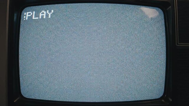 Old damaged VHS tape plays static noise with imperfect visuals in retro setting