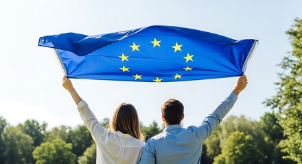 Couple holding european union flag with arms raised in sunny park travel europe people europe unity europe outdoors europe summer europe nature outdoors victory in europe day