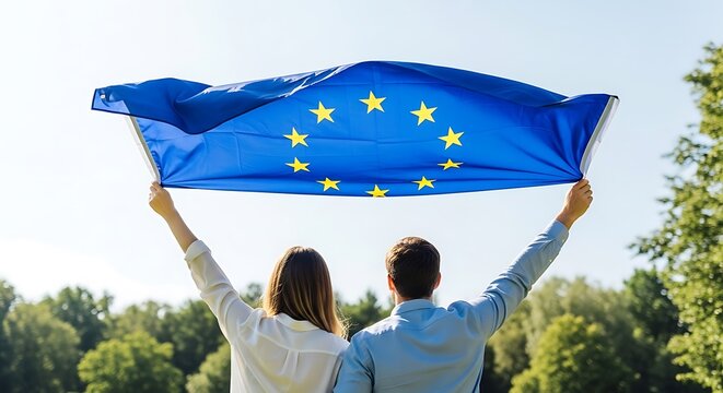 Couple holding european union flag with arms raised in sunny park travel europe people europe unity europe outdoors europe summer europe nature outdoors victory in europe day