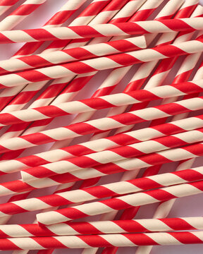 scattered red and white striped paper straws in full frame background, matte finish diagonal patterns in overlapping arrangement, top view
