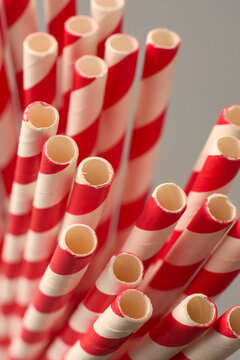 bundle of red and white striped paper straws on neutral background, matte finish drinking accessories, top view closeup macro