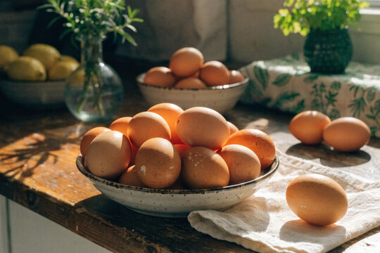 Fresh brown eggs in a bowl on a rustic kitchen table