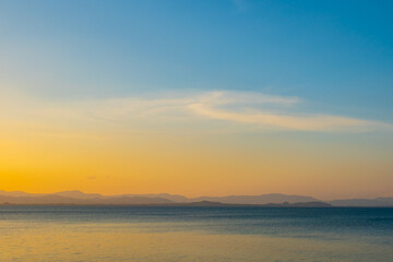 Obraz premium nature sky breathtaking golden sunset over a calm ocean, with the entire sky and water bathed in brilliant shades of yellow and orange. Streaky clouds enhance the dramatic display 