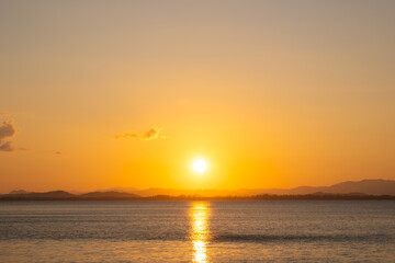 Obraz premium nature sky breathtaking golden sunset over a calm ocean, with the entire sky and water bathed in brilliant shades of yellow and orange. Streaky clouds enhance the dramatic display 