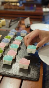 A Hand Picking Colorful Thai Jelly Desserts from a Buffet Tray