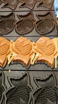 Chef Trimming Fresh Taiyaki Fish Shaped Cakes on a Hot Griddle